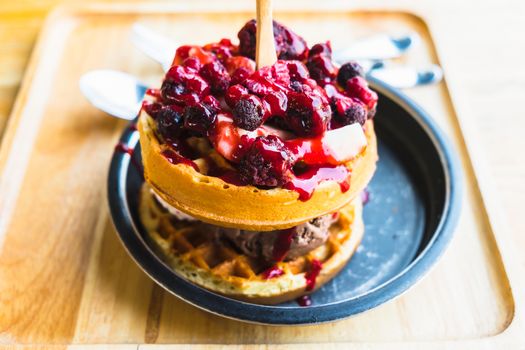 waffles and chocolate icecream with fresh berries on wooden tray