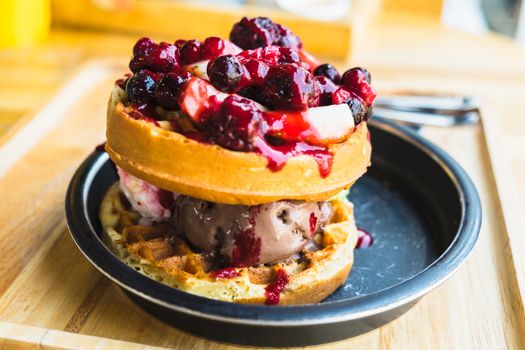 waffles and chocolate icecream with fresh berries on wooden tray