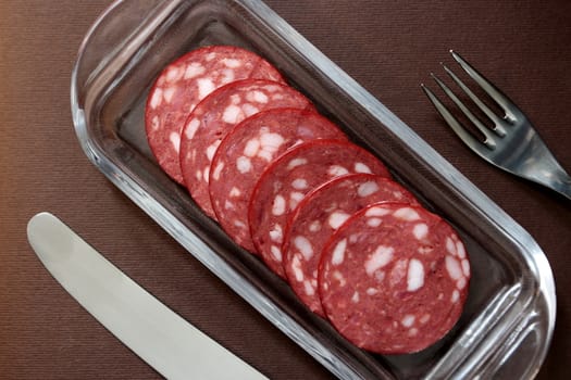 slices salami on a plate with cutlery