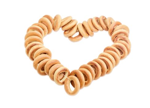 Bunch of small round bagels tied by cord and laid out in the form of heart on a light background 
