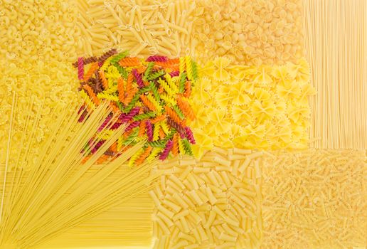 Background of several uncooked pasta different varieties, shapes and colors
