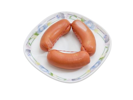 Bundle of three uncooked thick frankfurters on a dish on a light background
