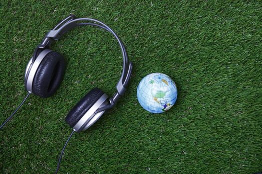 Headphone and earth globe on a grass