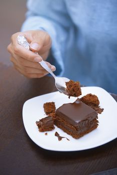 Hand of woman eating chocolate cake 