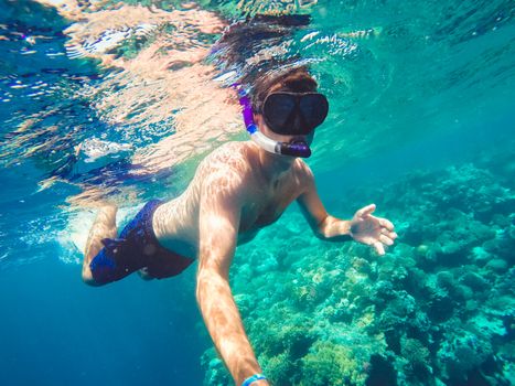 Underwater in the tropics paradise with snorkeling man, fish and coral reef, beautiful view on tropical sea. Safaga, Egypt. Holiday snorkeling vacation concept