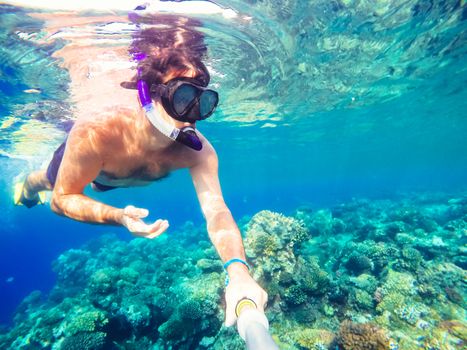 Underwater in the tropics paradise with snorkeling man, fish and coral reef, beautiful view on tropical sea. Safaga, Egypt. Holiday snorkeling vacation concept