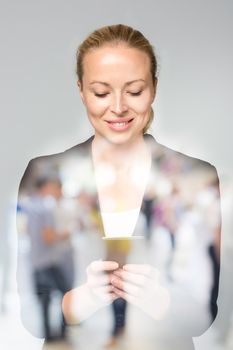 Beautiful young caucasian businesswoman in business attire using smart phone application. Double exposure with abstract blur of business people overlay.