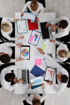 Team of business people working with graphs and diagrams sitting around the table