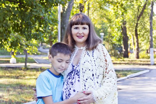 Pregnant mother and son in summer green park