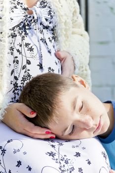 Head boy lying on knees of his pregnant mother