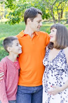 Happy family with pregnant mother in summer time