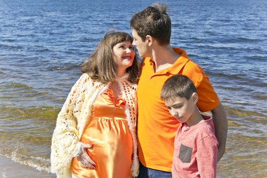 Happy husband looking to pregnant wife near river