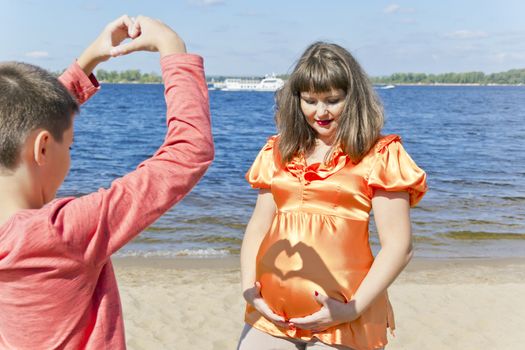 Happy boy with pregnant mother near river