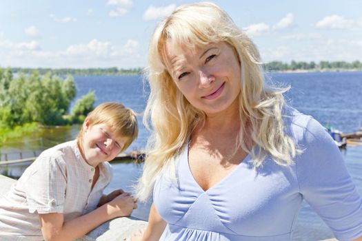 European woman in blue with son on the river background