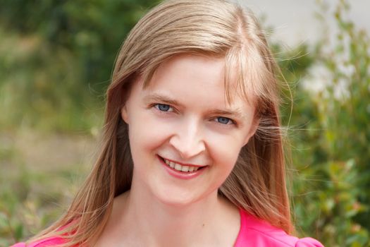 Blond smiling woman with long hair in summer