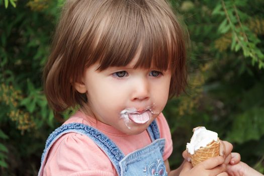 Cute baby girl are eating icecream in summer with put out tongue