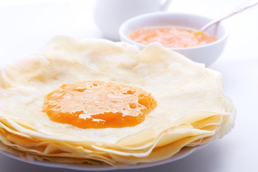 Crispy crepes with apricot jam served on a table