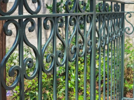 A dark green iron fence with curved design