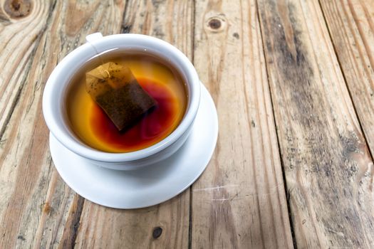 Cup of Hot Tea with Teabag on Grunge Wood Table Background