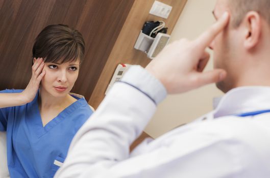 A female patient with headache in hospital worried is looking at doctor pointing his head.