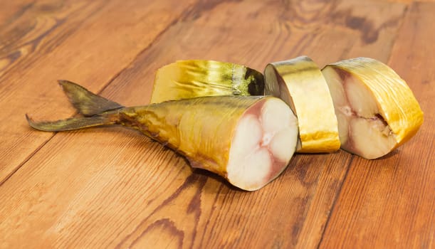 Tail portions and several other pieces of a cold-smoked Atlantic mackerel on a surface of an old wooden planks
