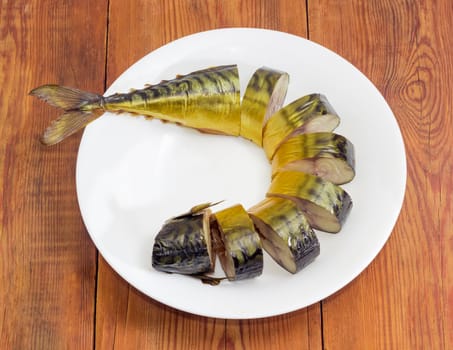 Sliced cold-smoked Atlantic mackerel on a white dish on an old wooden surface
