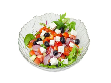 Greek salad in a glass salad bowl on a white background. 
