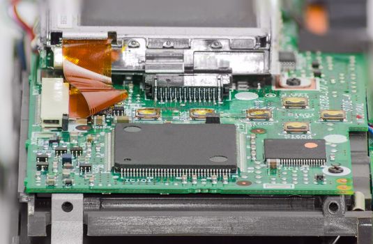 Fragment of electronic device with chips and other electronic components in foreground closeup
