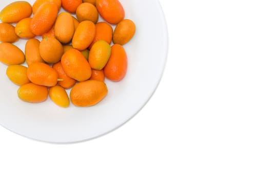 Top view of fragment of white dish with fresh oval kumquats closeup on a light background
