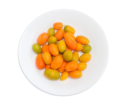 Top view of white dish with fresh oval kumquats closeup on a light background
