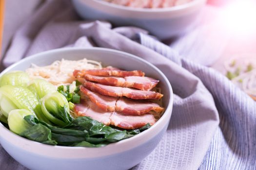 Instant noodles with shiitake mushrooms, pepper and onion in a bowl, Asian meal on a table.

