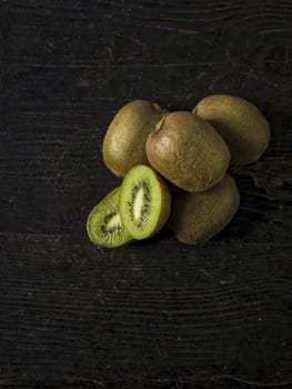 Kiwi fruit over a dark wooden table, shabby rustic mood.