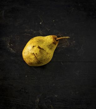 Pear over a dark wooden table, shabby rustic mood.