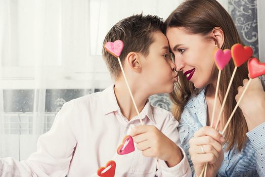 Happy Valentines Day or Mother day. Young boy spend time with her mum and celebrate with gingerbread heart cookies on a stick.