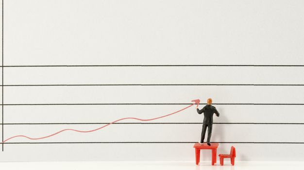 miniature man showing increase and grow of marketing by red graphic line