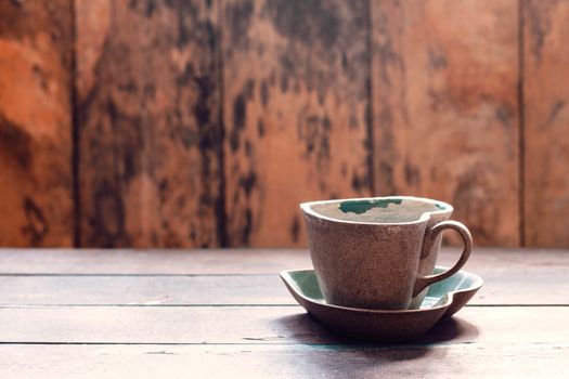 Cup and saucer of shaped heart on the old wooden.