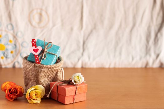 Gift bags and roses on a wooden table.
