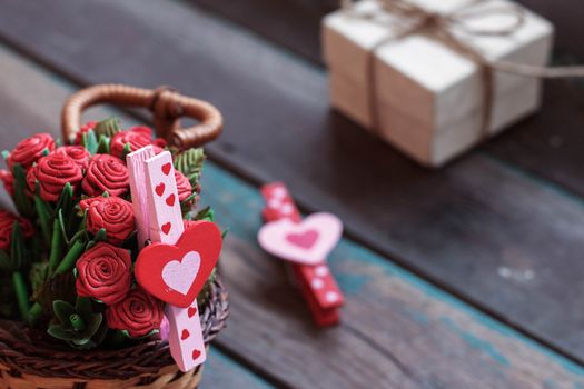 Heart-shaped and red flowers in basket on a wooden.