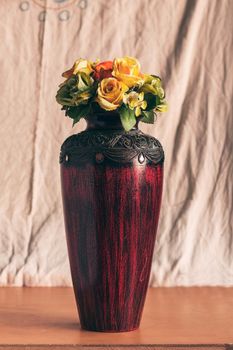 Roses in a vase on wooden table.