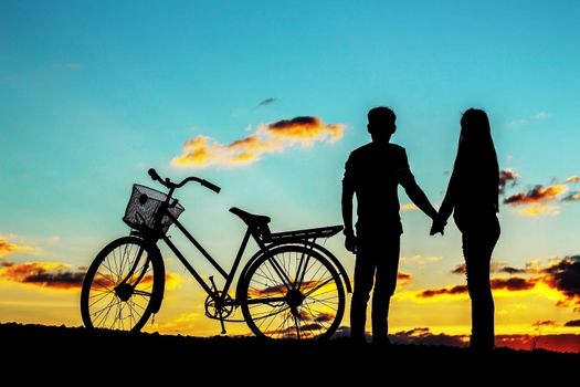 Young handshake and a bicycle at silhouettes.