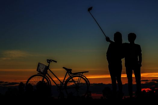 young man and girl of selfie and bicycles with silhouettes.
