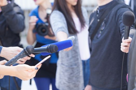 Journalists holding microphones, conducting media interview. News conference.