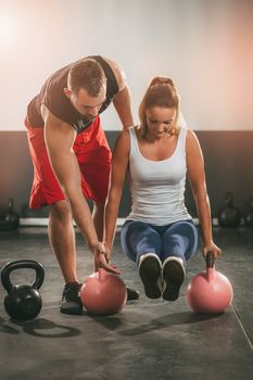 Young woman exercising at the gym with a personal trainer.