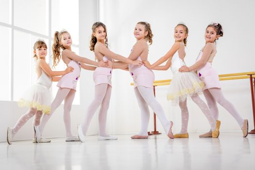 Little girls in dresses posing together at the ballet class. Looking at camera.