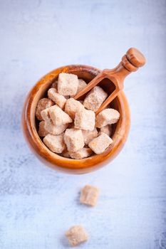 Brown cane sugar cubes in a wooden bowl.