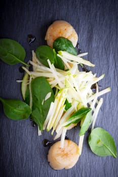 Scallop salad with apple, spinach on a stone plate 