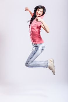 attractive young girl jumping, wearing pink hoodie and jeans