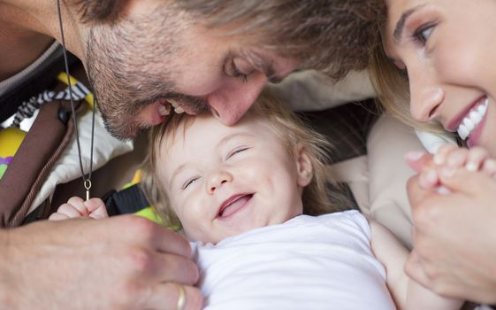 Couple of happy parents playing with their laughing baby. Close up of faces.