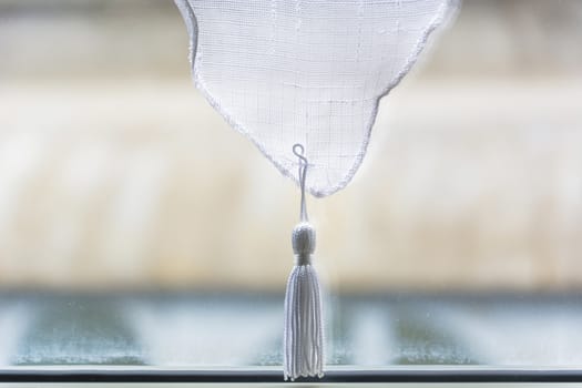 White tassel isolated on a dirty window