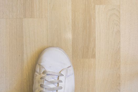White sneaker shoe on wooden floor background, top view